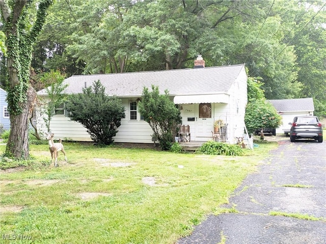 7567 Inland Dr, Olmsted Falls, OH 44138 - view of front of home with a front yard, a chimney, asphalt driveway, and a shingled roof