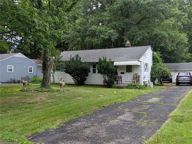 7567 Inland Dr, Olmsted Falls, OH 44138 - view of front of house featuring a front yard, a chimney, and roof with shingles