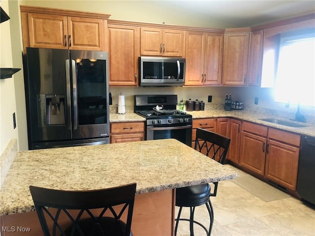 3700 Meander Reserve Cir, Canfield, OH 44406 - kitchen featuring appliances with stainless steel finishes, a breakfast bar area, light stone countertops, and brown cabinets