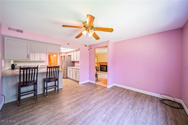 140 Fox Hollow Dr Unit 206C, Mayfield Heights, OH 44124 - kitchen with freestanding refrigerator, ceiling fan, a peninsula, light wood-style floors, and a breakfast bar area