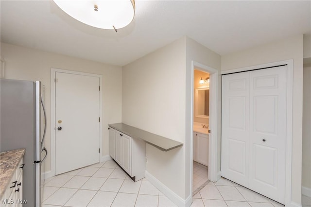 6131 Center St Unit 106, Mentor, OH 44060 - kitchen featuring freestanding refrigerator, light tile patterned flooring, and white cabinets