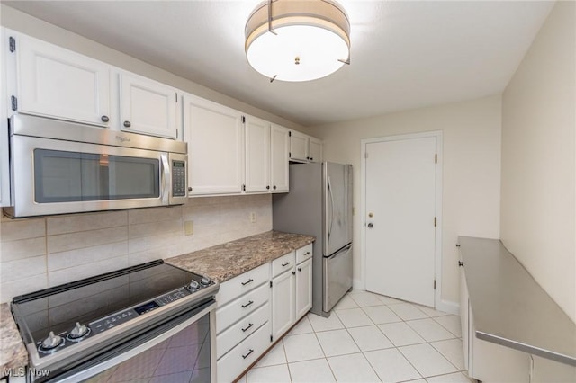 6131 Center St Unit 106, Mentor, OH 44060 - kitchen featuring appliances with stainless steel finishes, white cabinets, tasteful backsplash, light tile patterned floors, and light stone counters