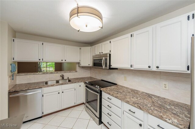 6131 Center St Unit 106, Mentor, OH 44060 - kitchen featuring appliances with stainless steel finishes, white cabinetry, backsplash, light stone countertops, and light tile patterned floors