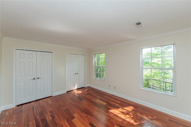 6131 Center St Unit 106, Mentor, OH 44060 - unfurnished bedroom featuring two closets, dark wood-style floors, and ornamental molding