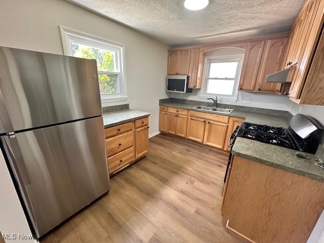 30115 Regent Rd, Wickliffe, OH 44092 - kitchen with freestanding refrigerator, a textured ceiling, under cabinet range hood, light wood-style floors, and plenty of natural light
