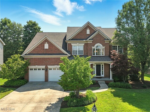 10421 Tolland Dr, Reminderville, OH 44202 - colonial-style house featuring concrete driveway, brick siding, a front lawn, a shingled roof, and an attached garage