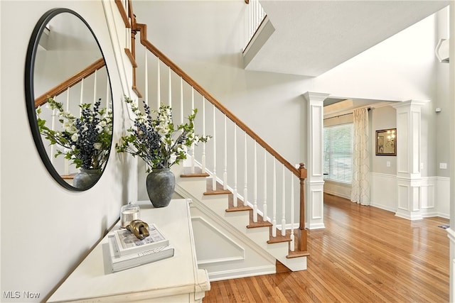 10421 Tolland Dr, Reminderville, OH 44202 - stairs featuring decorative columns, wood finished floors, a decorative wall, and a towering ceiling