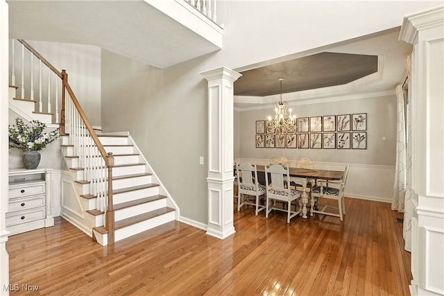 10421 Tolland Dr, Reminderville, OH 44202 - dining area featuring hardwood / wood-style flooring, stairs, a chandelier, ornate columns, and ornamental molding