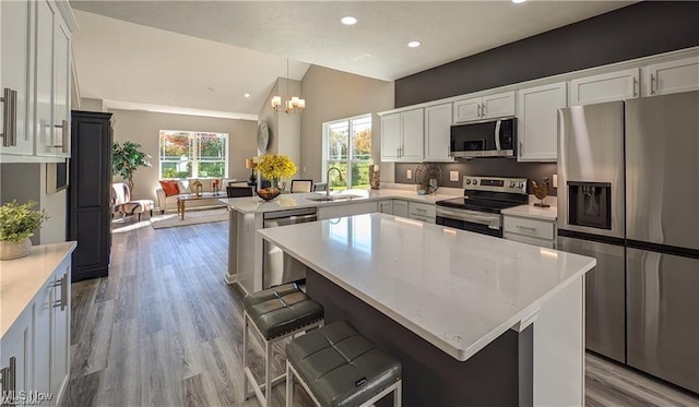 5007 Coventry Cir, Huron, OH 44839 - kitchen featuring appliances with stainless steel finishes, a peninsula, lofted ceiling, wood finished floors, and a chandelier