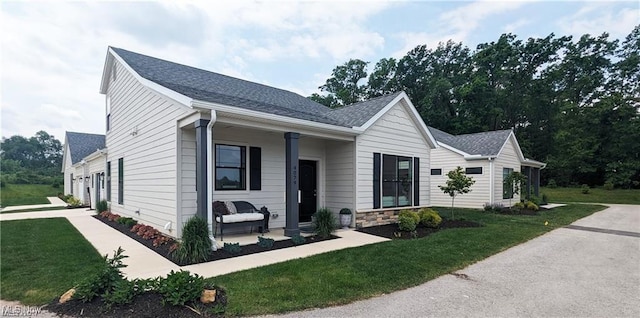 5007 Coventry Cir, Huron, OH 44839 - view of front facade featuring a front yard, roof with shingles, and covered porch