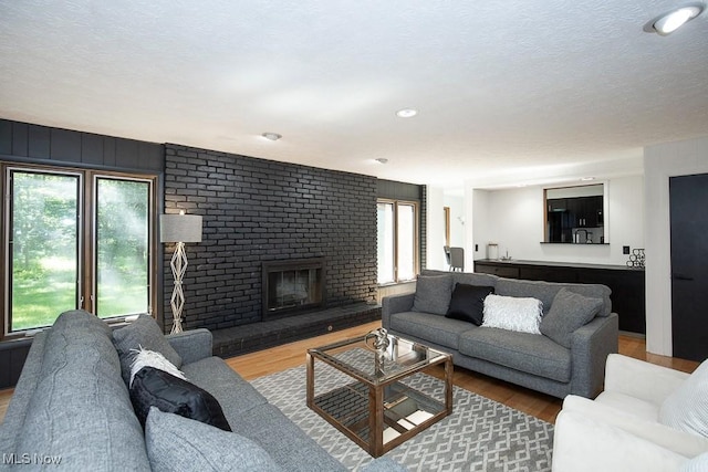 4280 Som Center Rd, Moreland Hills, OH 44022 - living room featuring plenty of natural light, a brick fireplace, wood finished floors, a textured ceiling, and recessed lighting