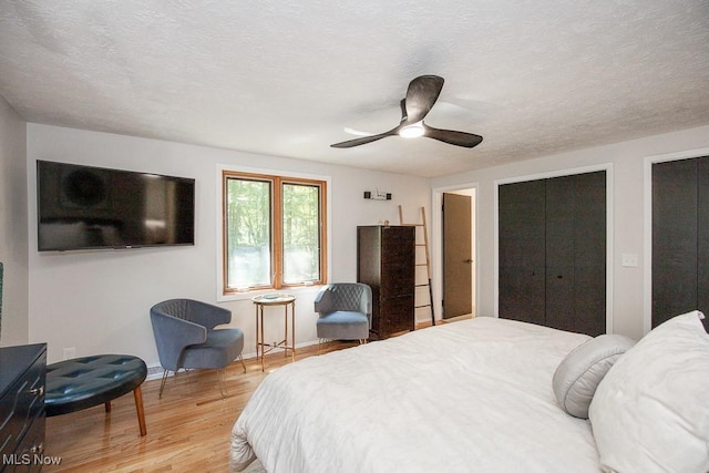 4280 Som Center Rd, Moreland Hills, OH 44022 - bedroom featuring light wood-style flooring, two closets, ceiling fan, and a textured ceiling