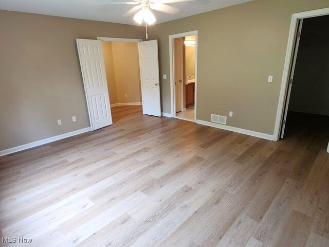 422 Dartmouth Trl, Sagamore Hills, OH 44067 - unfurnished bedroom featuring light wood-style floors, connected bathroom, a walk in closet, and ceiling fan