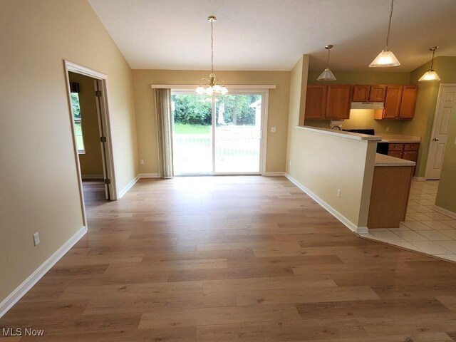 422 Dartmouth Trl, Sagamore Hills, OH 44067 - kitchen with lofted ceiling, under cabinet range hood, brown cabinets, a chandelier, and light countertops