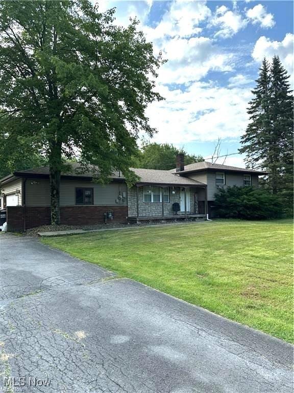 3123 S Duck Creek Rd, North Jackson, OH 44451 - split level home with a front yard, a chimney, asphalt driveway, and an attached garage