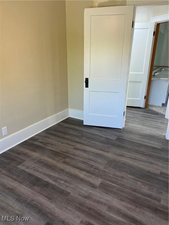 1820 E 47th St, Ashtabula, OH 44004 - unfurnished bedroom with baseboards and dark wood-style flooring