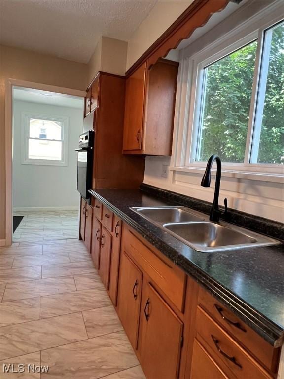 1820 E 47th St, Ashtabula, OH 44004 - kitchen featuring oven, brown cabinets, dark countertops, and a textured ceiling