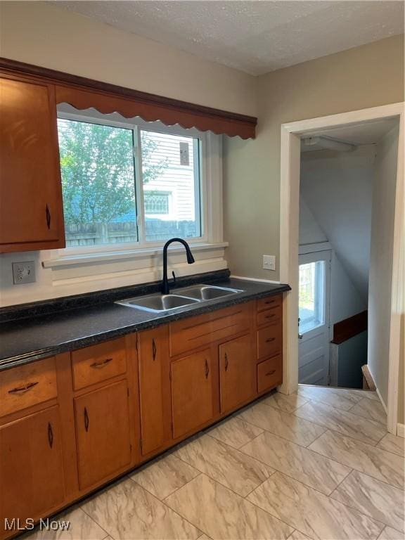 1820 E 47th St, Ashtabula, OH 44004 - kitchen with brown cabinets, light marble finish flooring, dark countertops, and a textured ceiling