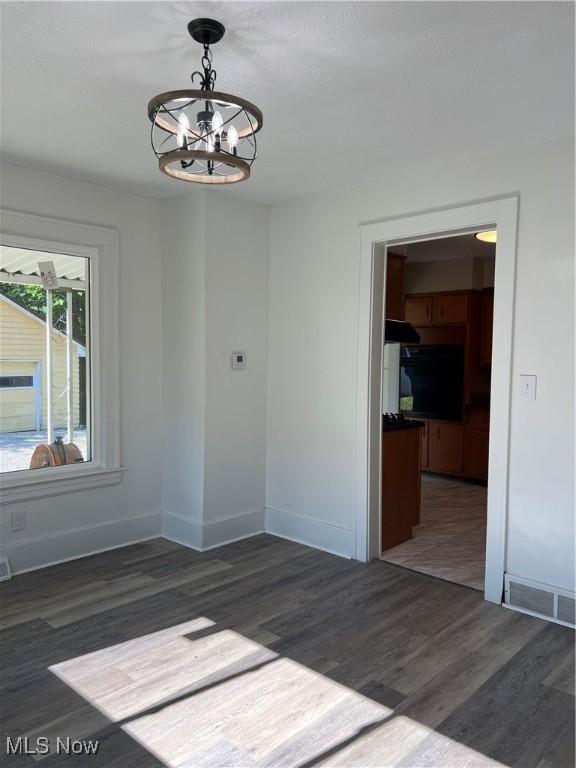 1820 E 47th St, Ashtabula, OH 44004 - spare room featuring a chandelier and dark wood-style flooring
