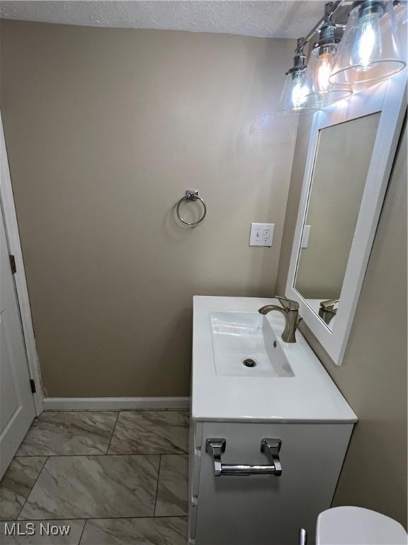 1820 E 47th St, Ashtabula, OH 44004 - bathroom with vanity, marble look tile flooring, and a textured ceiling