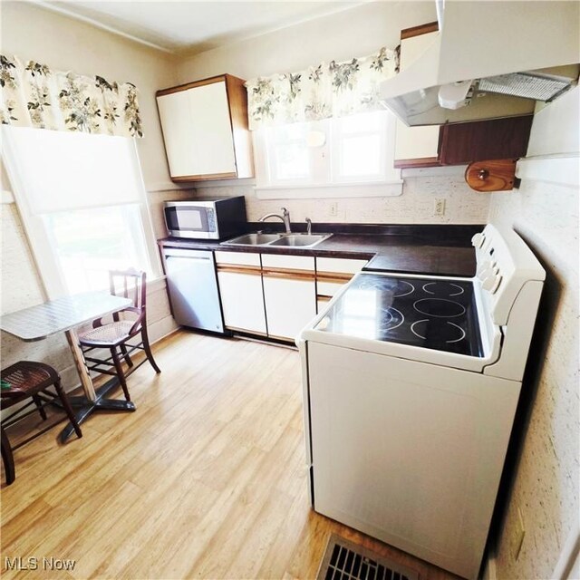 3303 Hemlock St, Parkersburg, WV 26101 - kitchen featuring stainless steel appliances, range hood, white cabinetry, light wood-style floors, and dark countertops
