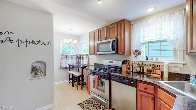 3622 Northcliffe Rd, University Heights, OH 44118 - kitchen featuring stainless steel appliances, brown cabinetry, dark countertops, a chandelier, and hanging light fixtures