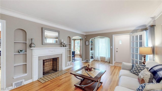 3622 Northcliffe Rd, University Heights, OH 44118 - living area featuring built in features, arched walkways, light wood-style floors, a fireplace with flush hearth, and crown molding