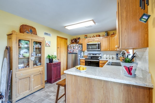 2207 Robinhood Dr, Wooster, OH 44691 - kitchen featuring appliances with stainless steel finishes, a peninsula, tasteful backsplash, light stone counters, and a kitchen bar