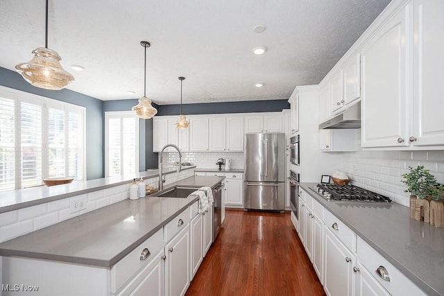 31008 Logan Ct, Westlake, OH 44145 - kitchen featuring appliances with stainless steel finishes, under cabinet range hood, backsplash, white cabinetry, and dark wood finished floors