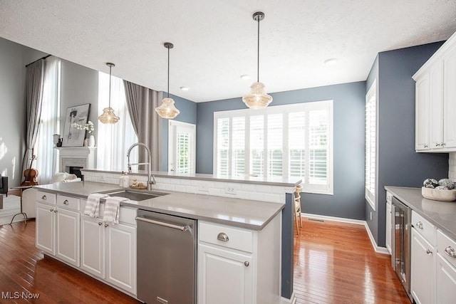 31008 Logan Ct, Westlake, OH 44145 - kitchen featuring stainless steel dishwasher, wood finished floors, beverage cooler, white cabinetry, and a center island with sink