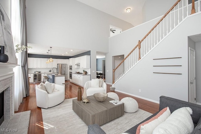 31008 Logan Ct, Westlake, OH 44145 - living area with light wood-type flooring, stairs, a brick fireplace, a high ceiling, and a ceiling fan