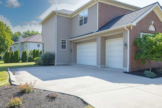 31008 Logan Ct, Westlake, OH 44145 - view of home's exterior with driveway, an attached garage, brick siding, and a shingled roof