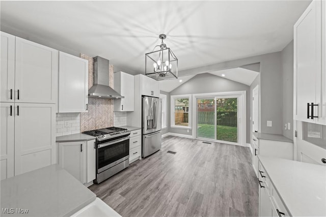 2905 Jay Ave, Cleveland, OH 44113 - kitchen featuring appliances with stainless steel finishes, wall chimney range hood, lofted ceiling, light countertops, and white cabinetry