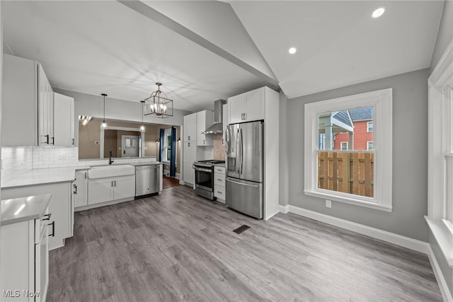 2905 Jay Ave, Cleveland, OH 44113 - kitchen with stainless steel appliances, wall chimney range hood, a chandelier, a peninsula, and white cabinets