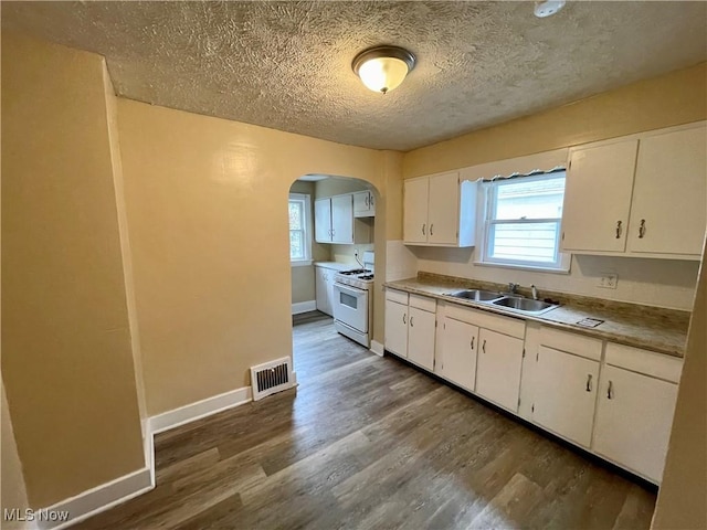 918 Silvercrest Ave, Akron, OH 44314 - kitchen featuring white range with gas cooktop, arched walkways, dark wood-style flooring, white cabinets, and a textured ceiling