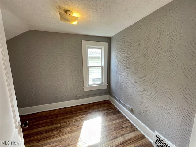 1072 Pitkin Ave, Akron, OH 44310 - empty room with wood finished floors, a textured ceiling, and lofted ceiling