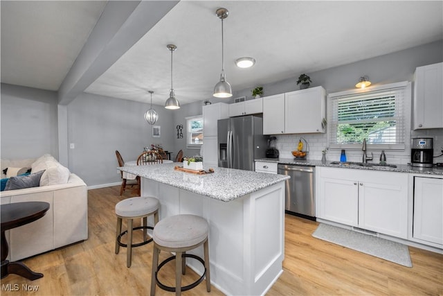 1921 Adrian Cir, Sandusky, OH 44870 - kitchen featuring appliances with stainless steel finishes, light wood-type flooring, a breakfast bar, light stone counters, and decorative backsplash