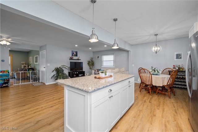1921 Adrian Cir, Sandusky, OH 44870 - kitchen featuring freestanding refrigerator, light wood-style flooring, white cabinets, pendant lighting, and a kitchen island