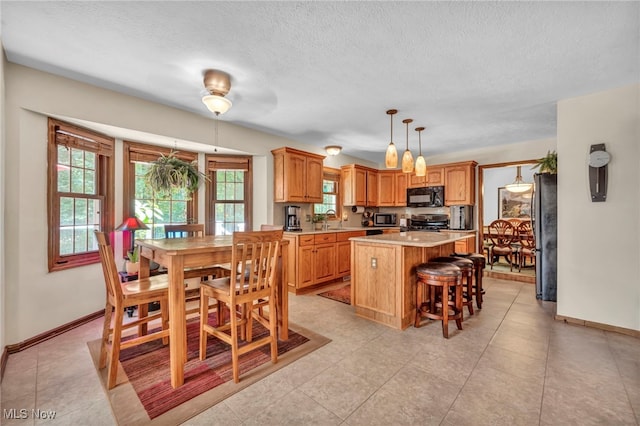 949 S Medina Line Rd, Wadsworth, OH 44281 - kitchen with stainless steel appliances, light countertops, a center island, a kitchen breakfast bar, and a textured ceiling