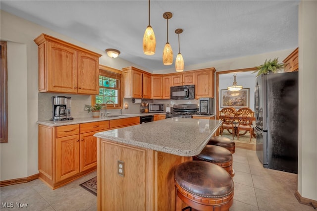 949 S Medina Line Rd, Wadsworth, OH 44281 - kitchen featuring black appliances, a kitchen island, a kitchen breakfast bar, light stone countertops, and light tile patterned floors