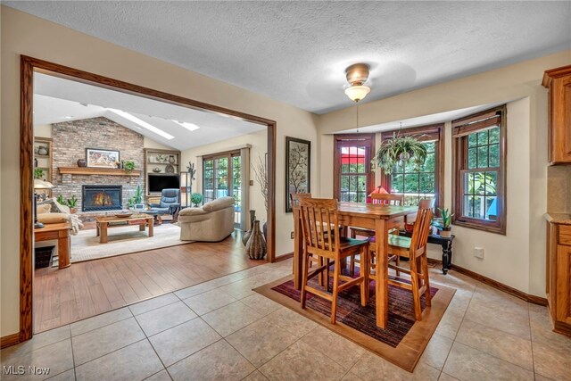 949 S Medina Line Rd, Wadsworth, OH 44281 - dining room featuring lofted ceiling, a fireplace, light tile patterned floors, and a textured ceiling