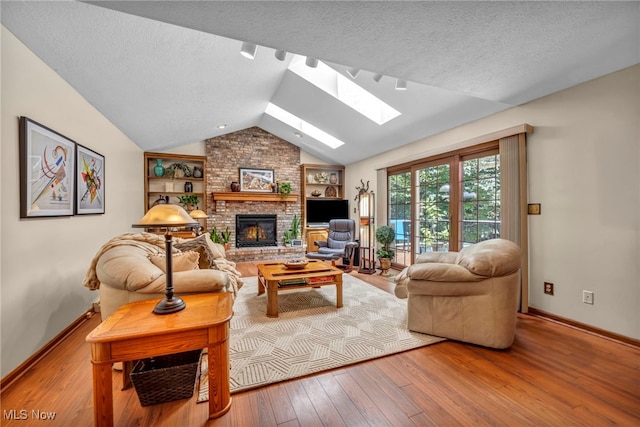 949 S Medina Line Rd, Wadsworth, OH 44281 - living area with a skylight, hardwood / wood-style floors, a brick fireplace, a textured ceiling, and lofted ceiling