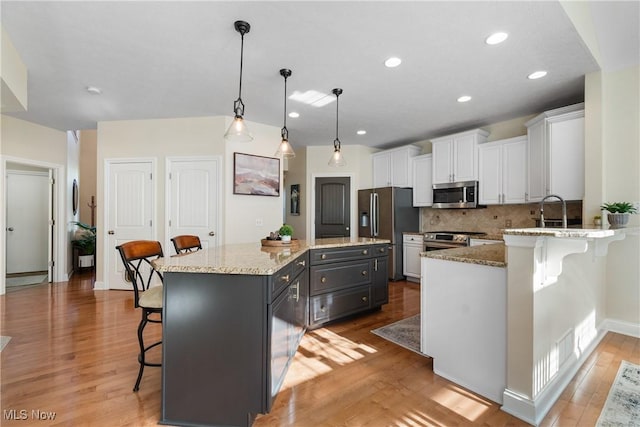 4276 Brownstone Ln, Medina, OH 44256 - kitchen featuring stainless steel appliances, a kitchen bar, white cabinets, light wood-style flooring, and decorative backsplash