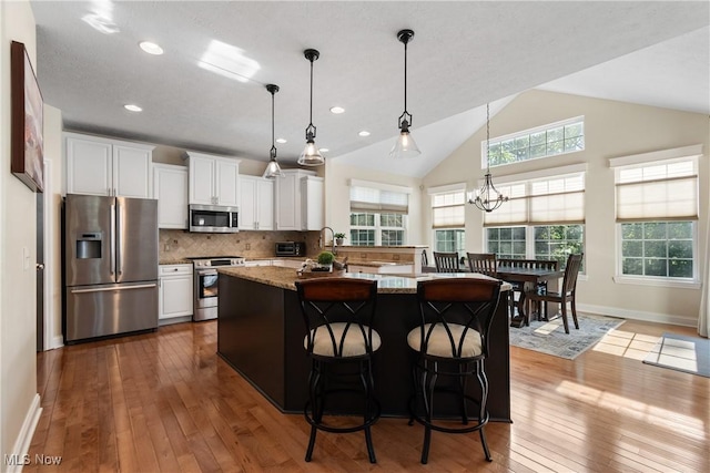 4276 Brownstone Ln, Medina, OH 44256 - kitchen featuring appliances with stainless steel finishes, dark wood-type flooring, white cabinetry, a kitchen island, and decorative backsplash