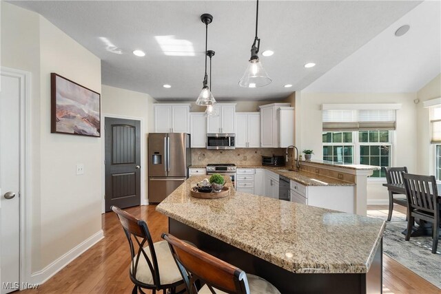 4276 Brownstone Ln, Medina, OH 44256 - kitchen featuring stainless steel appliances, tasteful backsplash, light wood-style flooring, white cabinets, and light stone countertops
