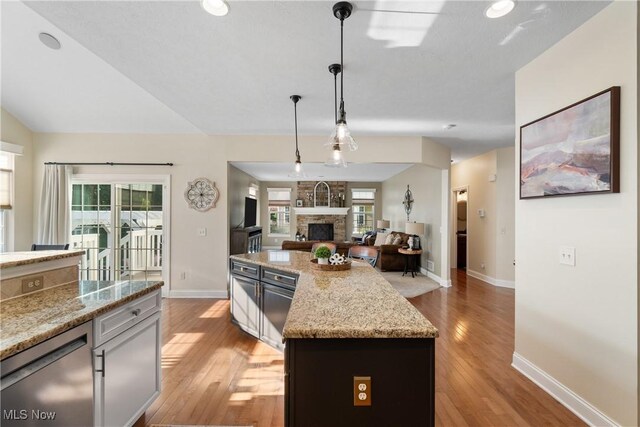 4276 Brownstone Ln, Medina, OH 44256 - kitchen with light wood finished floors, a fireplace, light stone counters, decorative light fixtures, and open floor plan
