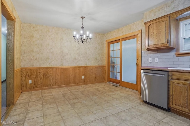 662 Beech Ave, Youngstown, OH 44512 - kitchen with stainless steel dishwasher, a chandelier, wainscoting, wooden walls, and brown cabinetry