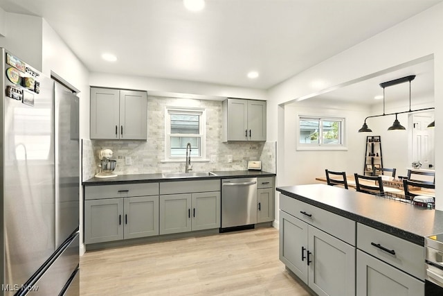 13806 Carpenter Rd, Garfield Heights, OH 44125 - kitchen with stainless steel appliances, gray cabinetry, dark countertops, light wood finished floors, and backsplash