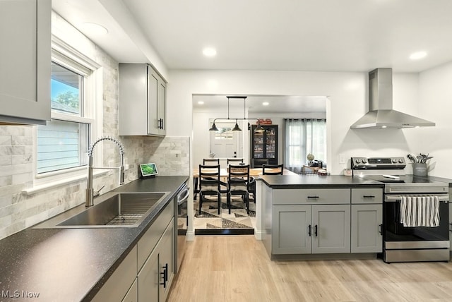 13806 Carpenter Rd, Garfield Heights, OH 44125 - kitchen with wall chimney exhaust hood, appliances with stainless steel finishes, dark countertops, gray cabinets, and light wood-style floors