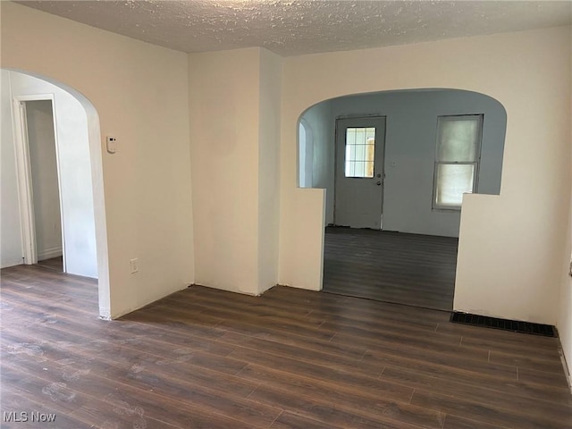 1122 W 17th St, Lorain, OH 44052 - empty room featuring arched walkways, dark wood finished floors, and a textured ceiling